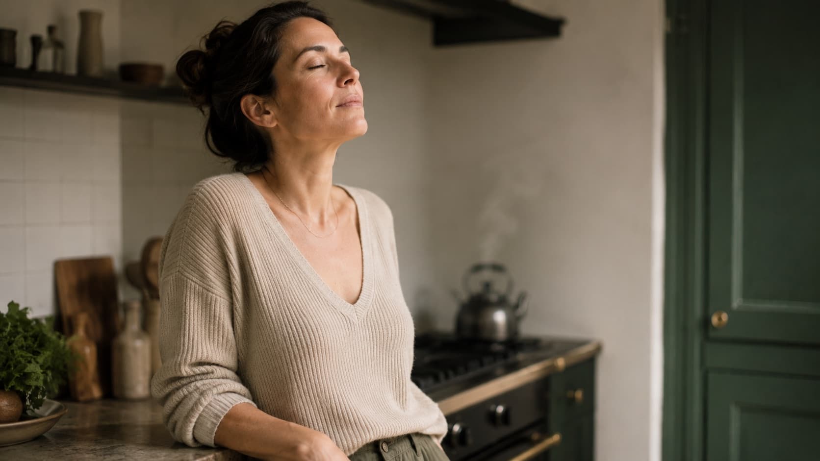 Una persona in cucina si ferma a fare un respiro, il bollitore sullo sfondo